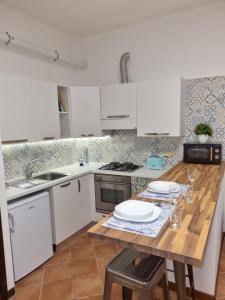 cocina con armarios blancos y mesa de madera en Giardino Moreno, en Palermo