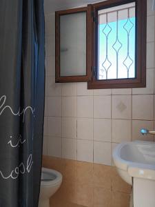 uma casa de banho com um lavatório, um WC e uma janela. em kir-Yiannis stonehouse @Areopoli em Areopoli