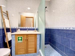 uma casa de banho com lavatório, WC e azulejos azuis em Mare Nostrum em Armação de Pêra