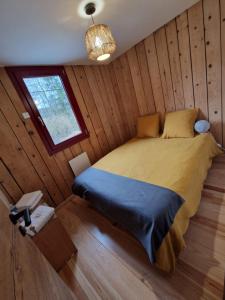 ein Schlafzimmer mit einem Bett in einem Holzzimmer in der Unterkunft Chalet de la forêt 1 à 6 pers in Saint-Sauveur