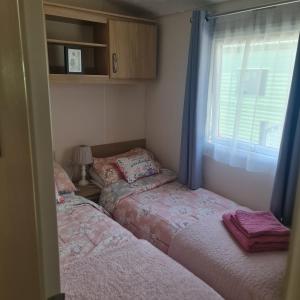 2 Betten in einem kleinen Zimmer mit Fenster in der Unterkunft Nicks, next door to Carmels in Carnforth