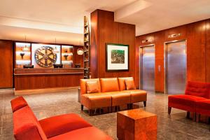 a waiting room with orange chairs and a clock at Four Points by Sheraton Manhattan Chelsea in New York