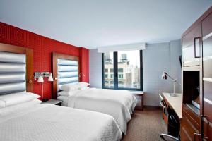 a hotel room with two beds and a red wall at Four Points by Sheraton Manhattan Chelsea in New York