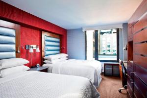 a hotel room with two beds and a red wall at Four Points by Sheraton Manhattan Chelsea in New York