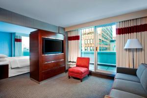 um quarto de hotel com uma cama, um sofá e uma televisão em The Chelsean New York em Nova York