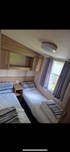 two beds in a small room with a window at 136 Beech at Flamingo Land in Malton