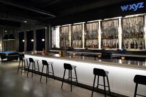 a bar with stools in a room with alcohol bottles at Aloft Charlotte Airport in Charlotte