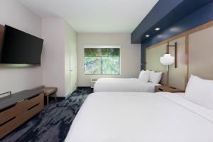 a hotel room with two beds and a flat screen tv at Fairfield Inn & Suites by Marriott Atlanta Stonecrest in Lithonia