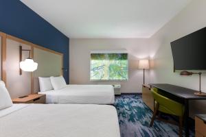 a hotel room with two beds and a desk at Fairfield Inn & Suites by Marriott Atlanta Stonecrest in Lithonia