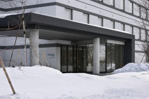 a building with snow in front of it at Fairfield by Marriott Hokkaido Eniwa in Eniwa