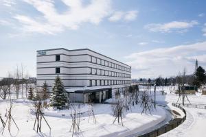 un grand bâtiment blanc dans la neige avec des arbres dans l'établissement Fairfield by Marriott Hokkaido Eniwa, à Eniwa