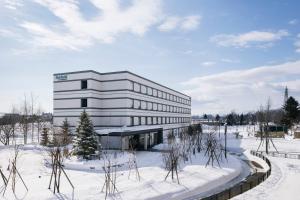a large white building in the snow with trees at Fairfield by Marriott Hokkaido Eniwa in Eniwa