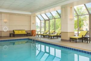 uma piscina no átrio do hotel com cadeiras e mesas em Sheraton Suites Chicago Elk Grove em Elk Grove Village