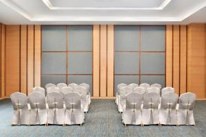 una sala de conferencias con sillas blancas y paredes de madera en Fairfield by Marriott Ahmedabad, en Ahmedabad