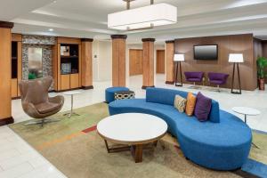 a lobby with a blue couch and a tv at Fairfield Inn & Suites Jacksonville Butler Boulevard in Jacksonville