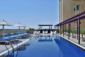 a hotel swimming pool with chairs and umbrellas at Fairfield by Marriott Amritsar in Amritsar