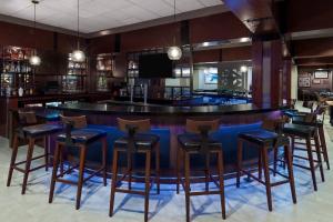 a bar with wooden stools and a blue counter at Four Points Huntsville Airport in Madison