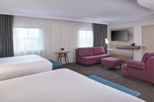 Habitación de hotel con 2 camas y muebles morados. en Delta Hotels by Marriott Detroit Novi, en Farmington Hills