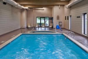 - une piscine avec une table et des chaises dans un bâtiment dans l'établissement Delta Hotels by Marriott Detroit Novi, à Farmington Hills