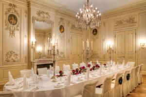 ケーニッヒスシュタイン・イム・タウヌスにあるVilla Rothschild, Autograph Collectionの長いテーブル、白い椅子、シャンデリアが備わる客室です。