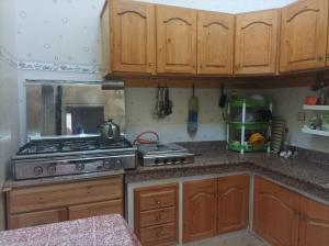 a kitchen with wooden cabinets and a stove at Jolie Maison pas chère in Oujda