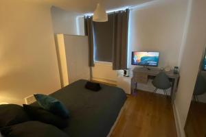 a bedroom with a bed and a desk with a television at 2 Bedroom Flat in Camberwell Green - Central Location with excellent connections to tourist attractions and main London airports in London