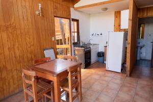 a kitchen with a wooden table and a refrigerator at Cabañas Lomas del Manzano in San José de Maipo