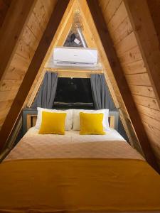 łóżko z 2 żółtymi poduszkami na poddaszu w obiekcie GÖCEK BUNGALOW w mieście Göcek