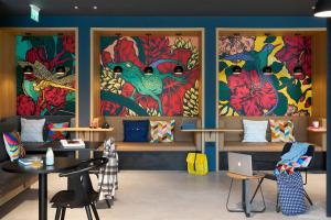 Moxy Bristol في بريستول: غرفة بها طاولات و لوحات ملونة على الجدران