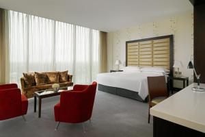 a hotel room with a large bed and red chairs at Sheraton Athlone Hotel in Athlone