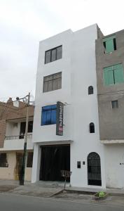 a white building with a blue window on it at Hostal Venus - Nueva Imagen in Huacho