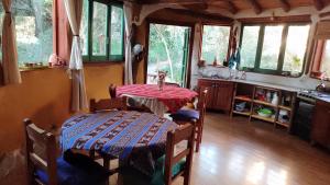 cocina con mesa y algunas ventanas y mesa en Habitación en Casa Ecológica en Villa Las Rosas