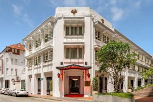 a white building on a street with cars parked in front at Maxwell Reserve Singapore, Autograph Collection in Singapore