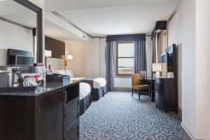 a hotel room with a bed and a desk and a television at Hotel Blackhawk, Autograph Collection in Davenport