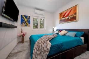 a bedroom with a bed and a flat screen tv at Uniquely designed Villa Ivana with outdoor Jacuzzi nearby the pebble Banje beach at the Island of Solta in Rogač