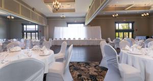 um salão de banquetes com mesas brancas e cadeiras brancas em Prestige Harbourfront Resort, WorldHotels Luxury em Salmon Arm