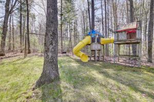 a playground with a yellow slide next to a tree at Roscommon Vacation Rental about 1 Mi to Higgins Lake! in Roscommon