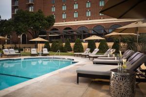 a pool with chairs and umbrellas next to a building at Renaissance Waterford Oklahoma City Hotel in Oklahoma City