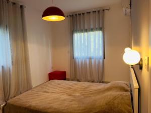 a bedroom with a bed and a lamp and a window at 2-bd apartment at the heart of the Carmel in Haifa