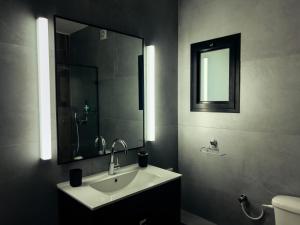 y baño con lavabo, espejo y aseo. en 2-bd apartment at the heart of the Carmel, en Haifa