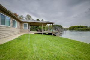 a house with a deck next to a body of water at Secluded Evart Vacation Rental on 82 Acres! in Evart