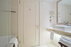 a white bathroom with a sink and a mirror at St. Pancras Renaissance Hotel London in London