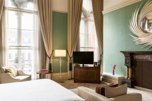 um quarto com uma cama, uma televisão e uma lareira em St. Pancras Renaissance Hotel London em Londres