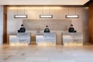 three men sitting at reception desks in a lobby at Courtyard by Marriott Seoul Pangyo in Seongnam