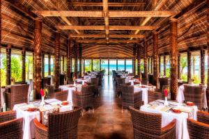 Sheraton Samoa Beach Resort في موليفانوا: مطعم بالطاولات البيضاء والكراسي والمحيط