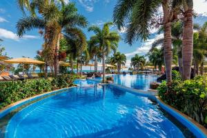 een zwembad in het resort met palmbomen bij Sheraton Samoa Beach Resort in Mulifanua