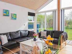 a living room with a black leather couch and a table at Three-Bedroom Holiday home in Hemmet 52 in Hemmet