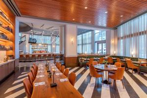 un restaurante con mesas y sillas de madera y ventanas en Renaissance Boston Waterfront Hotel, en Boston