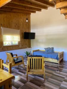 1 dormitorio con 1 cama, mesa y sillas en Cabaña Bigua en San Martín de los Andes