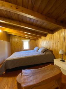 um quarto com uma cama num chalé de madeira em Cabaña Bigua em San Martín de los Andes